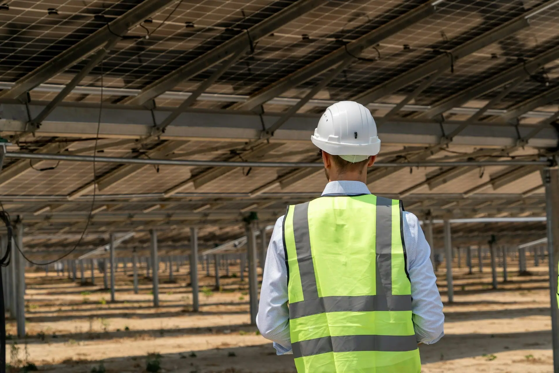 Engineer in a hard hat and safety vest inspecting a solar installation