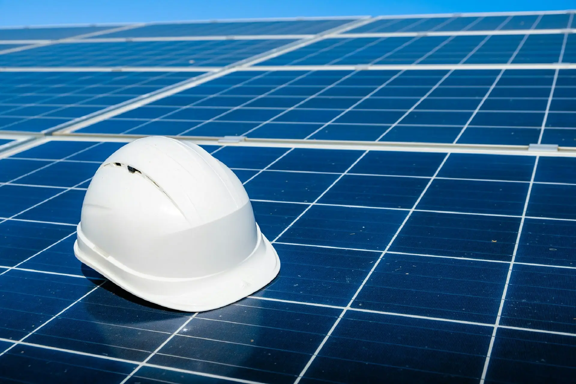 White safety helmet resting on a solar panel