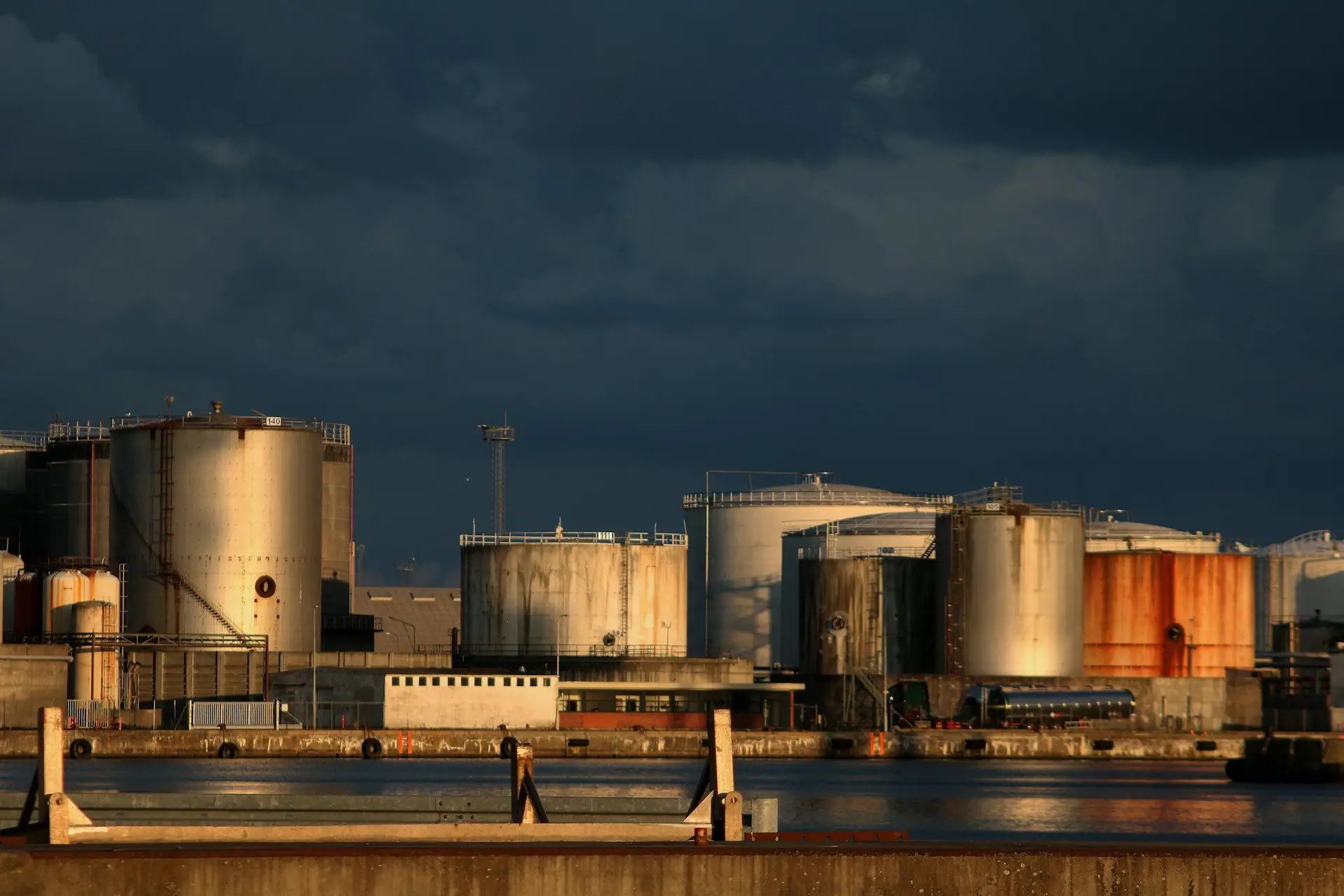 Waterfront storage tanks at an energy terminal under a dark sky